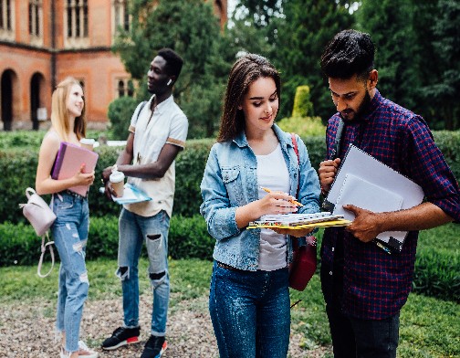 Three students talking to each other outdoor in a college courtyard.